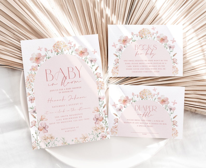 May include: Baby shower invitation featuring a floral design. The invitation reads "Baby in Bloom" and includes the name "Hannah Johnson". There are also two cards for guests to bring books or nappies for the baby.