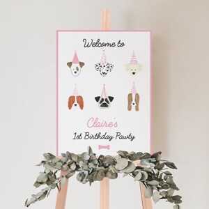 May include: A pink welcome sign with the text "Welcome to Claire's 1st Birthday Pawty" and illustrations of dogs wearing party hats.