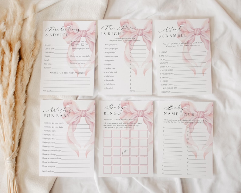 May include: A set of printable baby shower game cards featuring pink watercolor bows. The cards include games like "Predictions & Advice", "The Price is Right", "Word Scramble", "Wishes for Baby", "Baby Bingo", and "Baby Name Race".