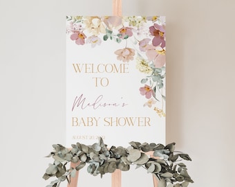May include: Welcome to Madison's Baby Shower sign with a floral design in shades of pink, yellow, and green. The sign is on a wooden easel.
