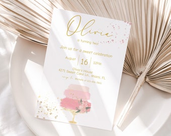 May include: A pink and gold birthday invitation for a child turning two. The invitation features a watercolor illustration of a pink cake with gold glitter and flowers. The text on the invitation reads "Olivia is turning two!" and includes the date, time, and location of the party.