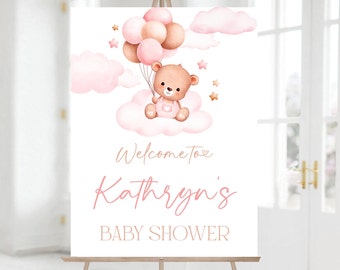 May include: Pink and brown baby shower welcome sign with a teddy bear holding balloons and a cloud. The sign says "Welcome to Kathryn's Baby Shower".