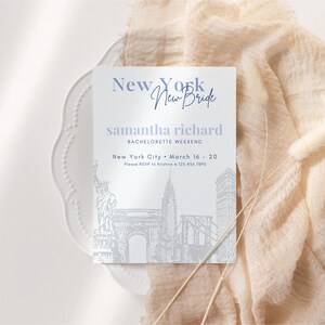 May include: A white invitation card with a blue and white illustration of the New York City skyline. The text on the card reads "New York New Bride Samantha Richard Bachelorette Weekend New York City March 16 - 20 Please RSVP to Kristina 123 456 7890".