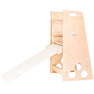 Puede incluir: Estructura de juego de madera con un tobog&aacute;n y una pared de escalada. La estructura est&aacute; hecha de madera natural y tiene un tobog&aacute;n blanco. La estructura tiene un recorte en forma de c&iacute;rculo en el lateral.