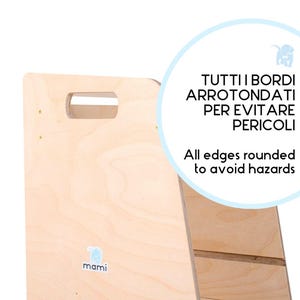 Puede incluir: Un taburete de madera con bordes redondeados para mayor seguridad. El taburete tiene un acabado de madera clara y un peque&ntilde;o logotipo de elefante en la parte delantera. El texto "TUTTI I BORDI ARROTONDATI PER EVITARE PERICOLI" est&aacute; escrito en italiano en un c&iacute;rculo azul. El texto "All edges rounded to avoid hazards" est&aacute; escrito en ingl&eacute;s en el c&iacute;rculo azul.