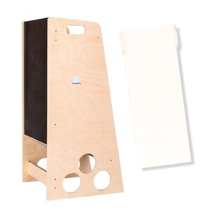 Puede incluir: Un taburete de madera con un panel de pizarra negra en la parte delantera. El taburete tiene un asa recortada en la parte superior y tres agujeros redondos en la parte inferior. El taburete est&aacute; etiquetado con "mami" en azul.