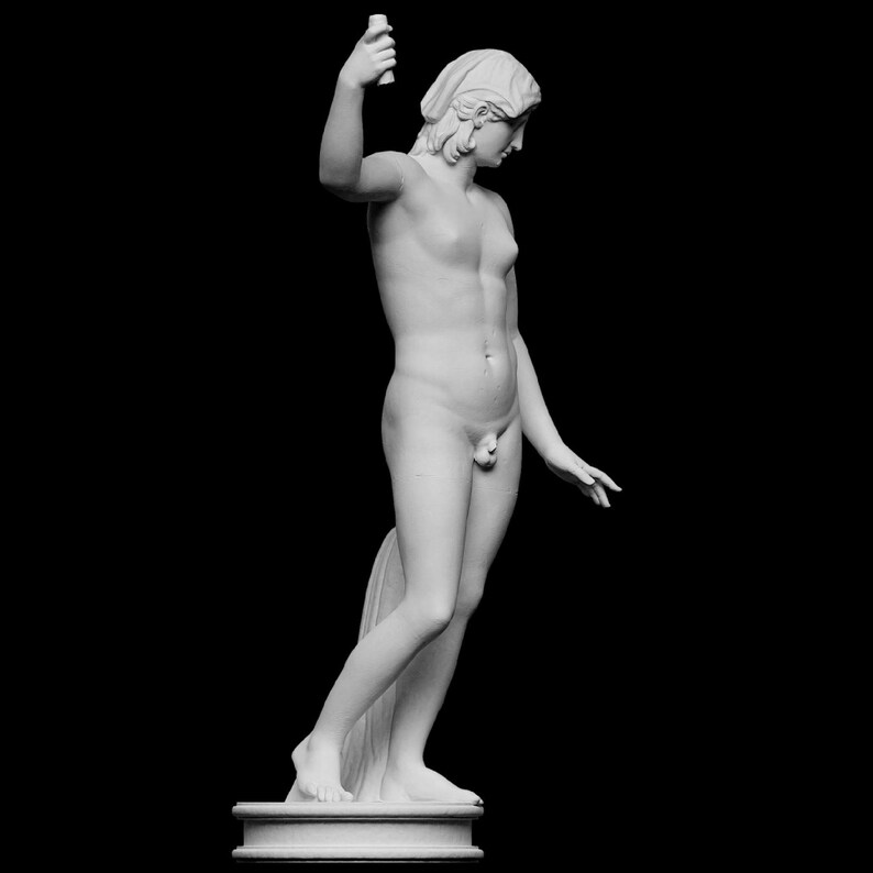A small white 3D sculpture print of the Statue of Liberty is placed between two potted plants.