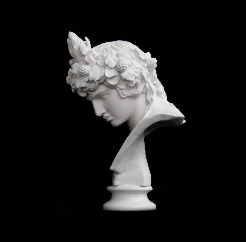 May include: White plaster bust of a person with a floral crown, the bust is on a white pedestal.