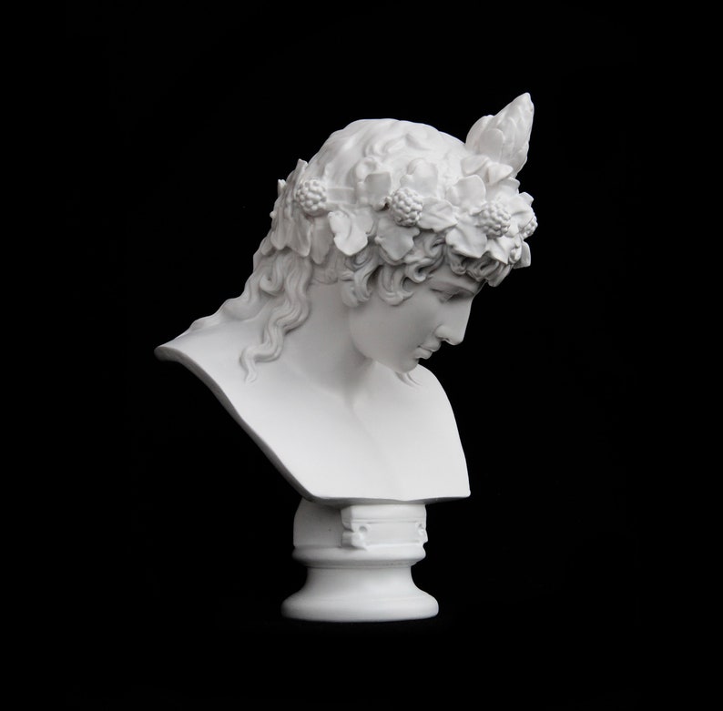 May include: White plaster bust of a woman with a wreath of leaves and berries on her head. The bust is on a pedestal.