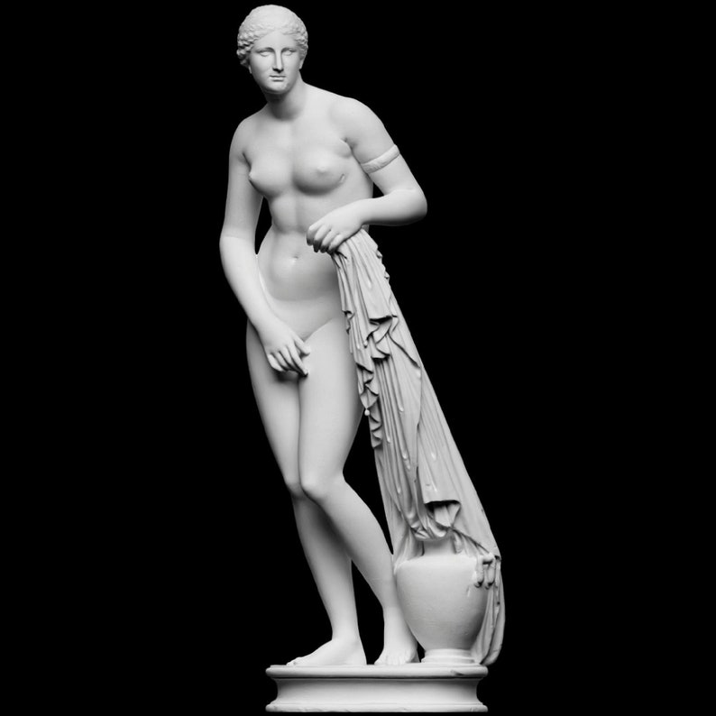 May include: A white marble statue of a woman standing with a drapery draped over her arm. The statue is on a white pedestal.