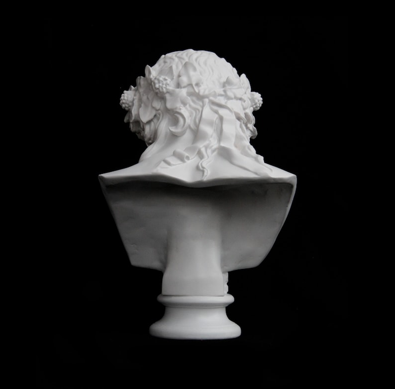 May include: White plaster bust of a woman with a floral crown, viewed from the back. The bust is on a pedestal.