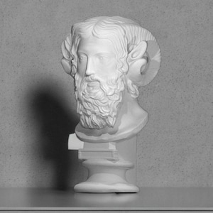 Op de afbeelding: Witte gipsen buste van een man met een baard en hoorns. De buste staat op een voetstuk.