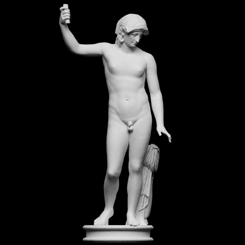 A small white 3D sculpture print of the Statue of Liberty is placed between two potted plants.