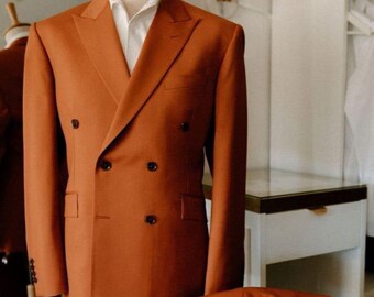 May include: A burnt orange double-breasted suit with a white dress shirt. The suit is displayed on a mannequin, with the matching trousers resting below. The text "STITCH Art And Design" is visible in the upper left corner.