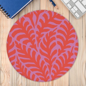 May include: A round pink and orange mouse pad with a repeating pattern of stylized leaves.