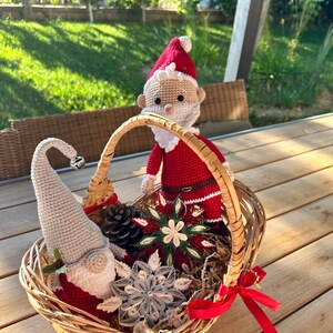 May include: A wicker basket filled with a crocheted Santa Claus and gnome, paper snowflakes, and a pine cone.
