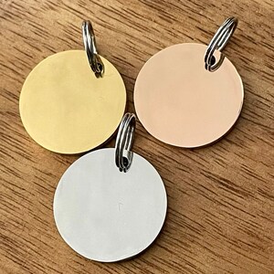 May include: Three round metal dog tags with key rings. The tags are gold, silver, and rose gold.