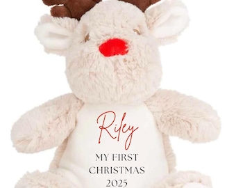 May include: A plush reindeer toy with a cream-colored body, brown antlers, and a red nose. The text "Riley, MY FIRST CHRISTMAS 2025" is printed in red script on the reindeer's chest. The toy is designed for Christmas.