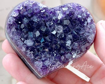 May include: A heart-shaped amethyst crystal cluster with a purple and white colour scheme. The crystal is polished and has a smooth surface.