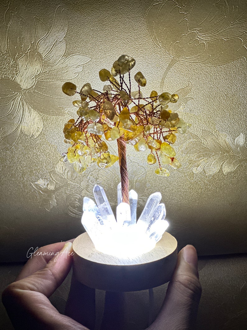 May include: A crystal tree with a copper wire base and clear quartz crystals in a wooden base. The tree is decorated with yellow citrine stones.