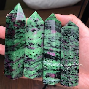May include: Four green, black, and pink zultanite crystal points. The points are faceted and have a smooth, polished finish.