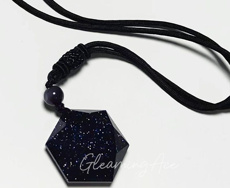 May include: A black necklace with a dark blue, star-shaped pendant. The pendant is made of a glittery material.