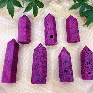 May include: Seven purple crystal-shaped objects with a textured surface. The objects are arranged in a row on a wooden surface.