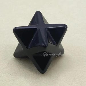 Puede incluir: Un cristal de color azul oscuro en forma de estrella de cinco puntas. El cristal es liso y pulido, con un acabado brillante.