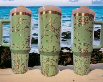 May include: Three stainless steel travel mugs with a light green finish and silver shark and sea life designs. The mugs have lids and handles.