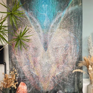 May include: Large wall tapestry with a central design featuring a white, multi-lined figure against a dark background with teal and blue accents. The artwork is surrounded by plants and decorative items.