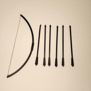 May include: A black bow and arrow set with seven arrows. The bow is made of a flexible material and the arrows are made of a hard plastic.