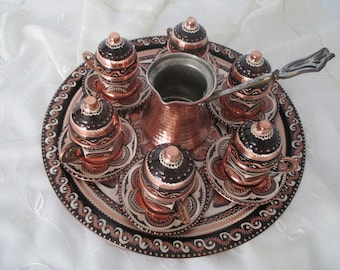 May include: A copper coffee set with six cups, saucers, and lids, a coffee pot, and a serving tray. The set features intricate black and copper designs. The tray is approximately 30 cm in diameter.
