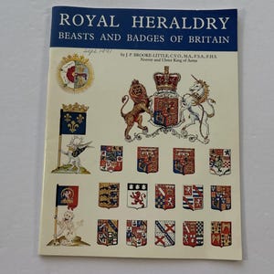 May include: A vintage book cover titled "Royal Heraldry: Beasts and Badges of Britain." The cover features illustrations of heraldic crests, flags, and a royal coat of arms, with text in a dark blue banner at the top.