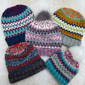 May include: Five knitted hats with different colourful patterns. The hats are made with a variety of yarns and have different textures. Some of the hats have pom-poms.