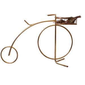 May include: A gold metal decorative stand shaped like a bicycle with a round basket on the handlebars.