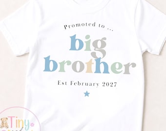 May include: White t-shirt with the text "Promoted to... big brother Est February 2027" in blue, green, and gray lettering. A small blue star is below the text. The shirt has short sleeves and a round neckline.