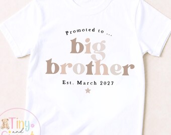 May include: A white short-sleeved t-shirt featuring the text Promoted to big brother in brown and beige lettering, with the text Est. March 2027 and a small star symbol printed below. The design is centered on the front of the garment.