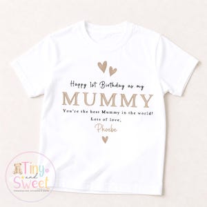 May include: A white short-sleeved t-shirt featuring the text "Happy 1st Birthday as my MUMMY. You're the best Mummy in the world! Lots of love, Phoebe" in black and tan lettering, accented with three small tan heart illustrations.