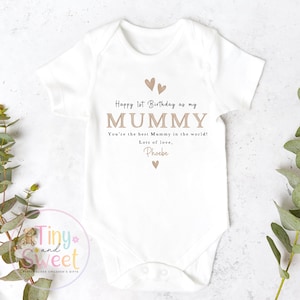 May include: A white short-sleeved baby bodysuit featuring the text Happy 1st Birthday as my MUMMY, You're the best Mummy in the world! Lots of love, Phoebe, accented with small tan heart icons printed in a centered, clean, and legible font style.
