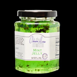 May include: A glass jar of green mint jelly with a white label that reads "Osborn Acres Mint Jelly Gluten Free GF Net Wt 12 oz (340g)"