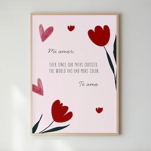 May include: A framed art print with a pale pink background. The print features red tulip illustrations and heart shapes. Text in black script reads "Mi amor: Ever since our paths crossed, the world has had more colour. Te amo."