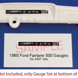 May include: A white plastic model car dashboard with gauge decals. The gauges are black, red, and white. A separate card reads "1965 Ford Fairlane 500 Gauges for AMT kits."