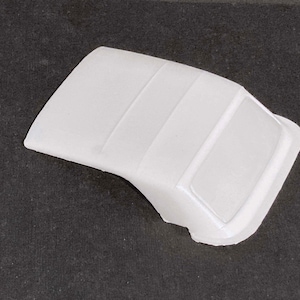 May include: White plastic model car roof with a rear window. The roof has three raised lines running down the center.
