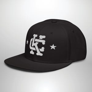 May include: Black baseball cap with a white embroidered logo featuring the letters "KC" and two stars.