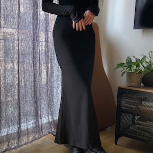 K&ouml;nnte beinhalten: Ein schwarzes, schulterfreies Maxikleid mit langen &Auml;rmeln. Das Kleid hat einen figurbetonten Oberteil und einen flie&szlig;enden Rock.