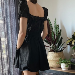May include: A black, short-sleeved dress with a square neckline and a ruffled bodice. The dress has a fitted waist and a flowing skirt.