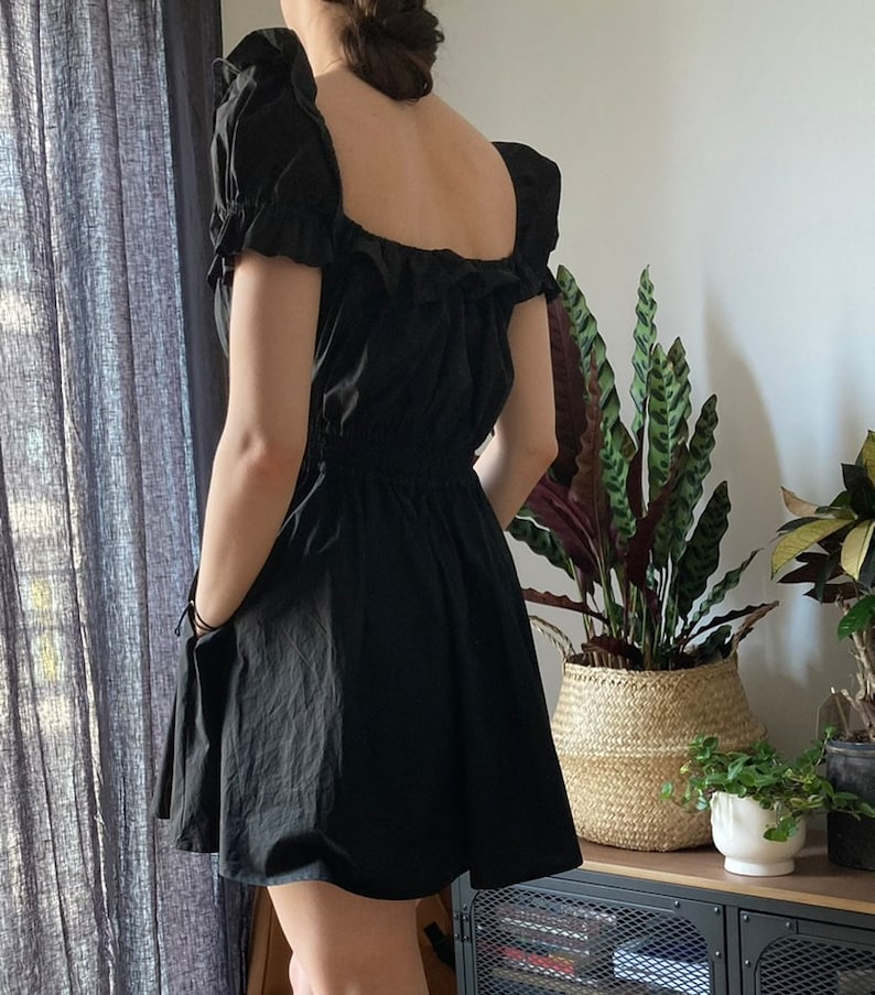 May include: A black, short-sleeved dress with a square neckline and a ruffled bodice. The dress has a fitted waist and a flowing skirt.