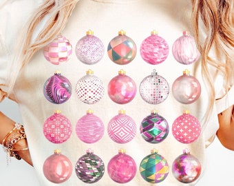 May include: A white t-shirt with a pink and white Christmas ornament design. The ornaments are arranged in a grid pattern and feature various geometric designs.