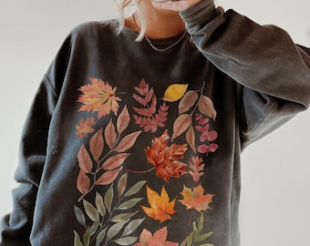 May include: A dark gray sweatshirt with a colorful autumn leaf design. The leaves are in shades of red, orange, yellow, and green.