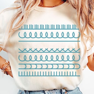 May include: Ivory-colored t-shirt with a turquoise geometric design. The design features horizontal rows of various shapes, including straight lines, wavy lines, and connected loops. The shirt is made of a soft material and is suitable for casual wear.